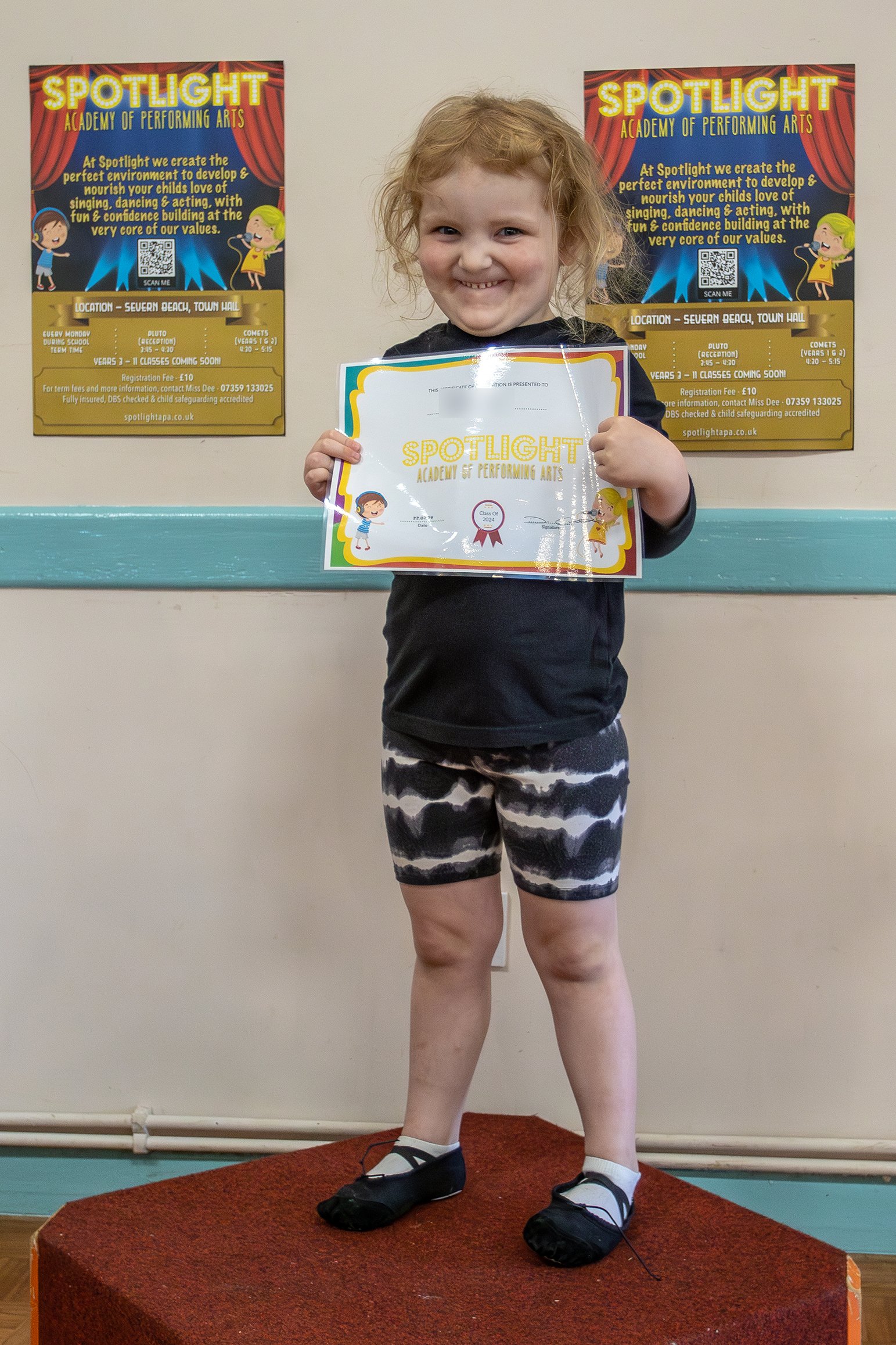 A young performer proudly holding a Spotlight certificate